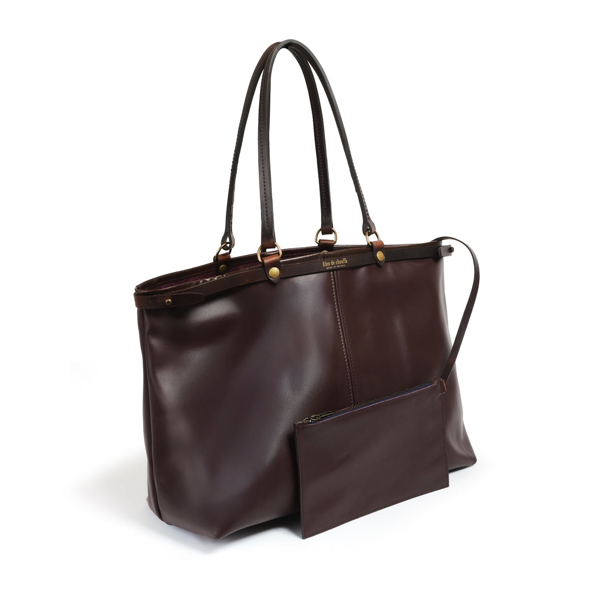 A dark brown leather tote bag with dual top handles, a front zippered pocket, and a matching detachable shoulder strap, shown on a clean white background.